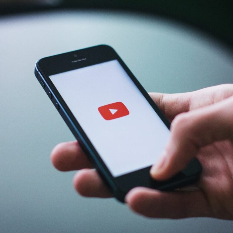 Someone holding a smartphone that is showing the YouTube logo.