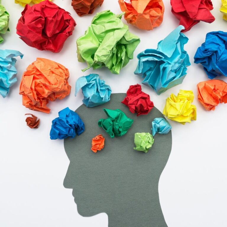 A silhouette of a head with crumpled colourful papers coming out of it.